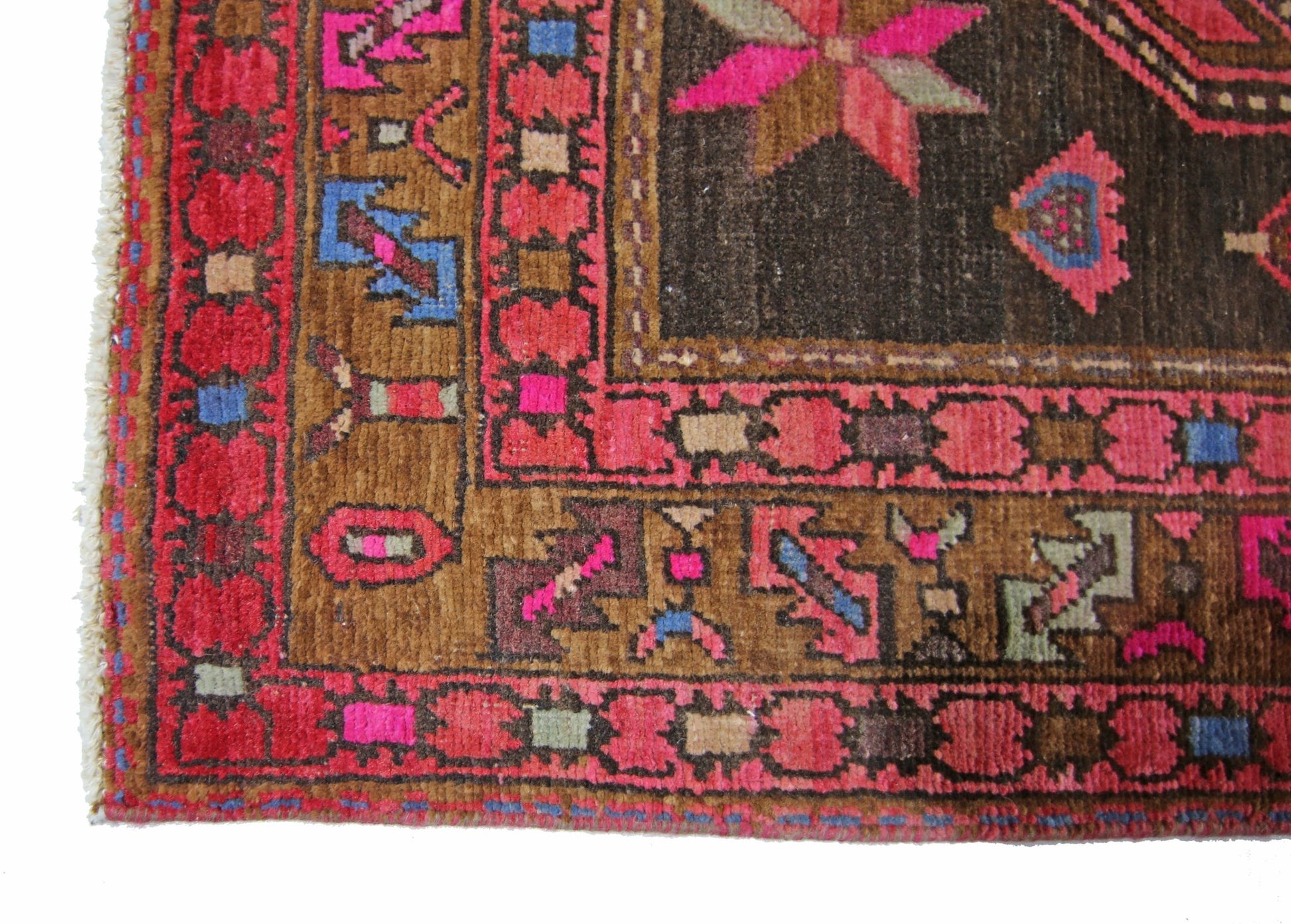 A vintage Persian Ardabil rug featuring a geometric pattern in vibrant pink, blue, and brown tones.