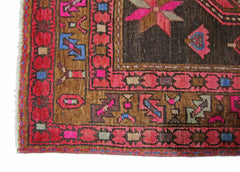 A vintage Persian Ardabil rug featuring a geometric pattern in vibrant pink, blue, and brown tones.