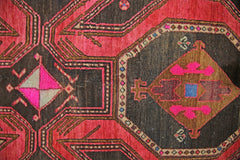 A vintage Persian Ardabil rug featuring a geometric pattern in vibrant red, brown, and pink tones.