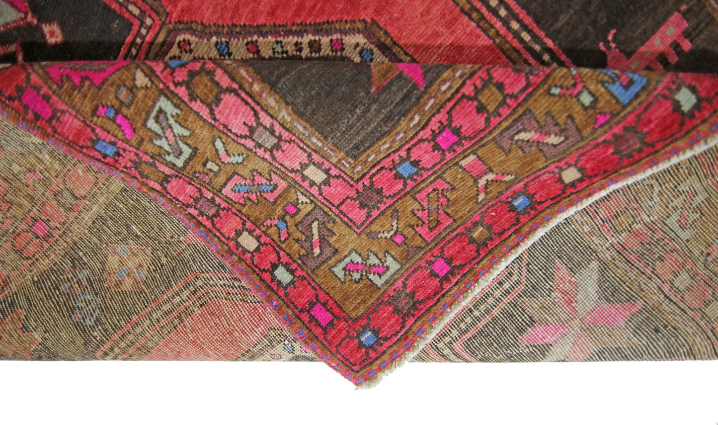 A vintage Persian Ardabil rug featuring a geometric pattern in vibrant red, brown, and pink tones.