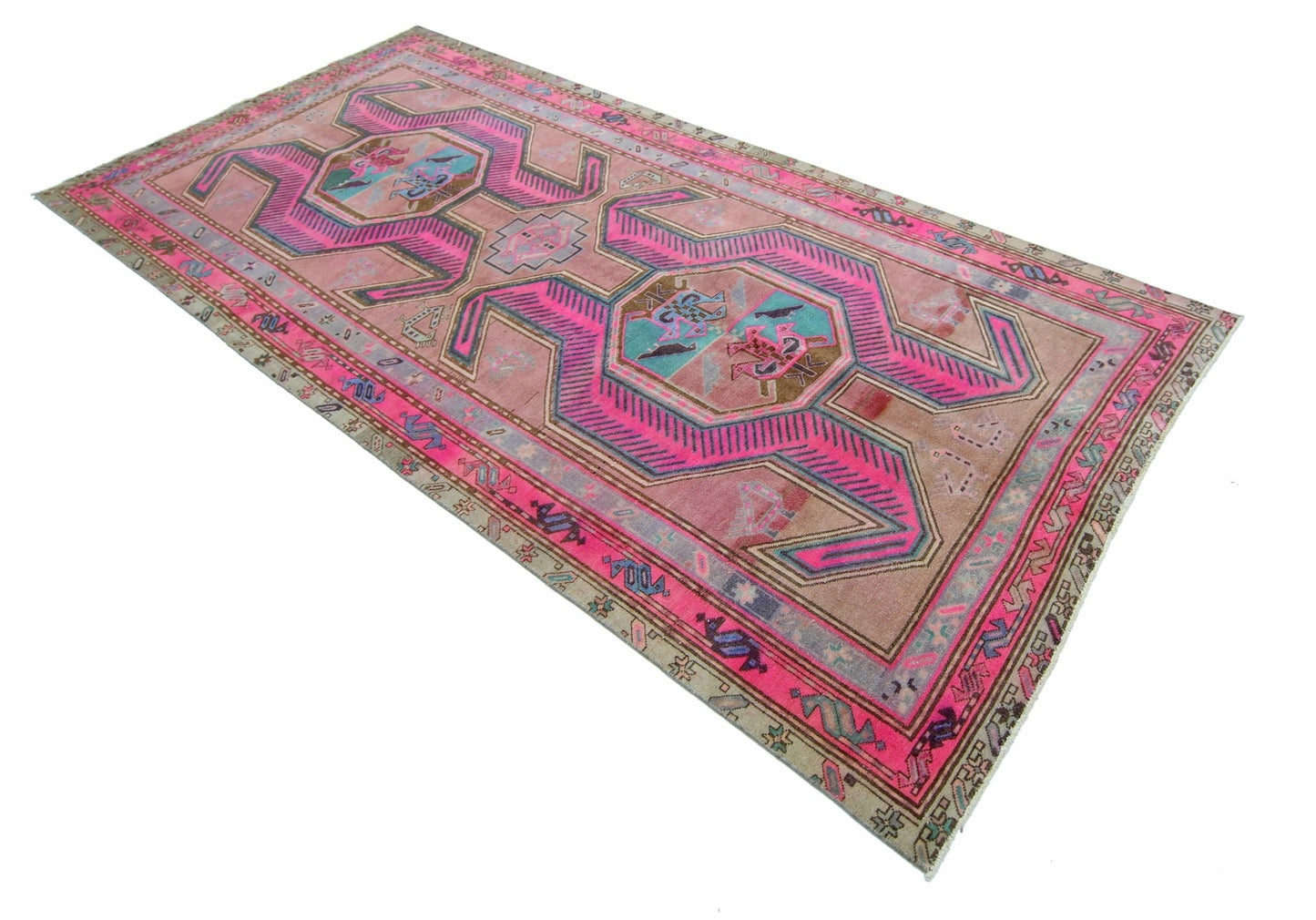 A vintage Persian Ardabil rug featuring a geometric pink pattern on a muted brown background.