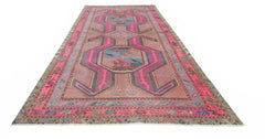 A vintage Persian Ardabil rug featuring a geometric pattern in vibrant pink and muted earth tones.