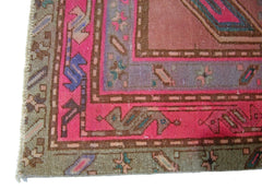 A vintage Persian Ardabil rug featuring a vibrant pink border and intricate geometric patterns.