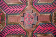 A vintage Persian Ardabil rug featuring a geometric pattern in vibrant pink, brown, and grey.