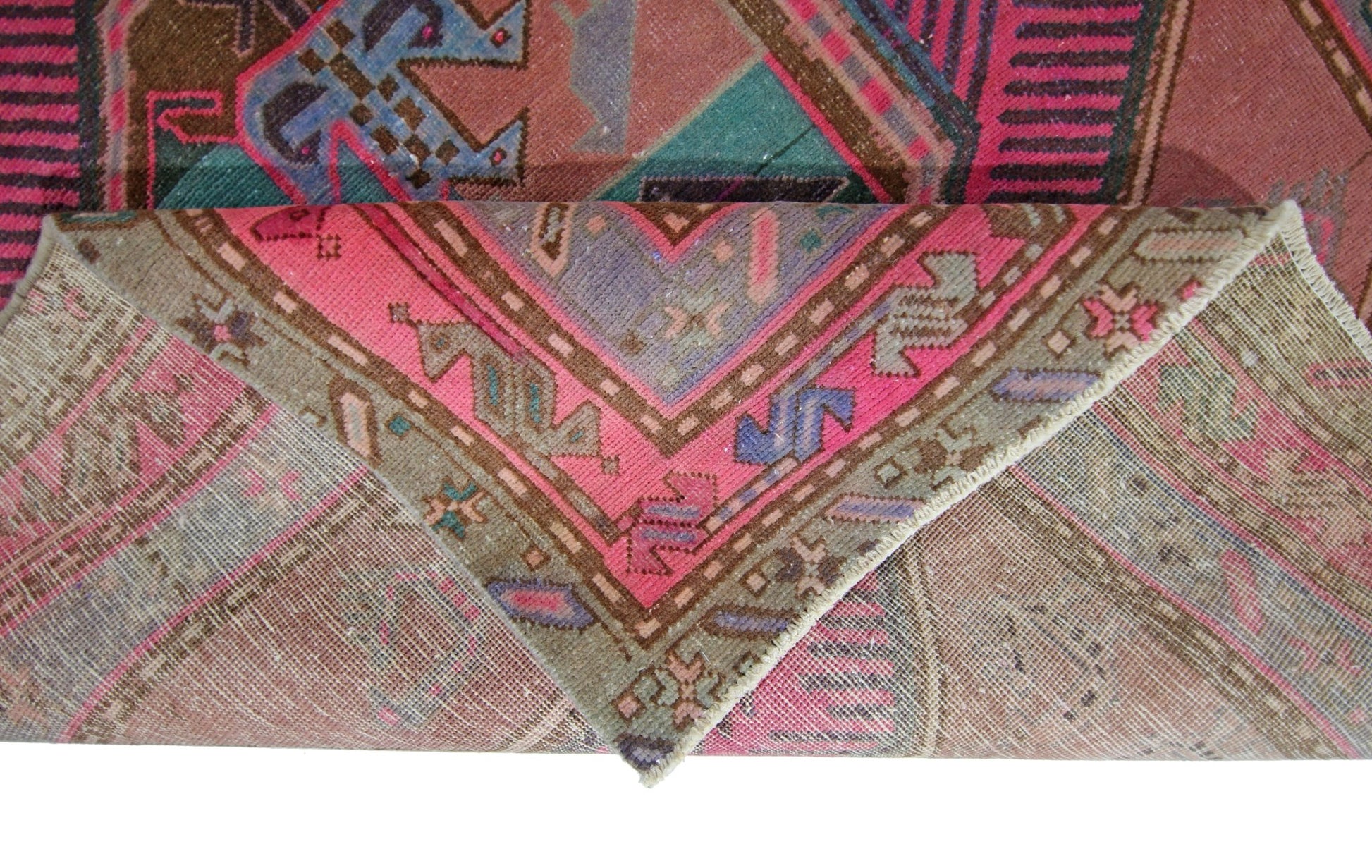 A vintage Persian Ardabil rug featuring a geometric pattern in vibrant pink, blue, and brown tones.