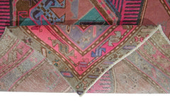 A vintage Persian Ardabil rug featuring a geometric pattern in vibrant pink, blue, and brown tones.