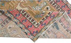 A vintage Persian Ardabil rug featuring a folded corner with intricate geometric and floral patterns.