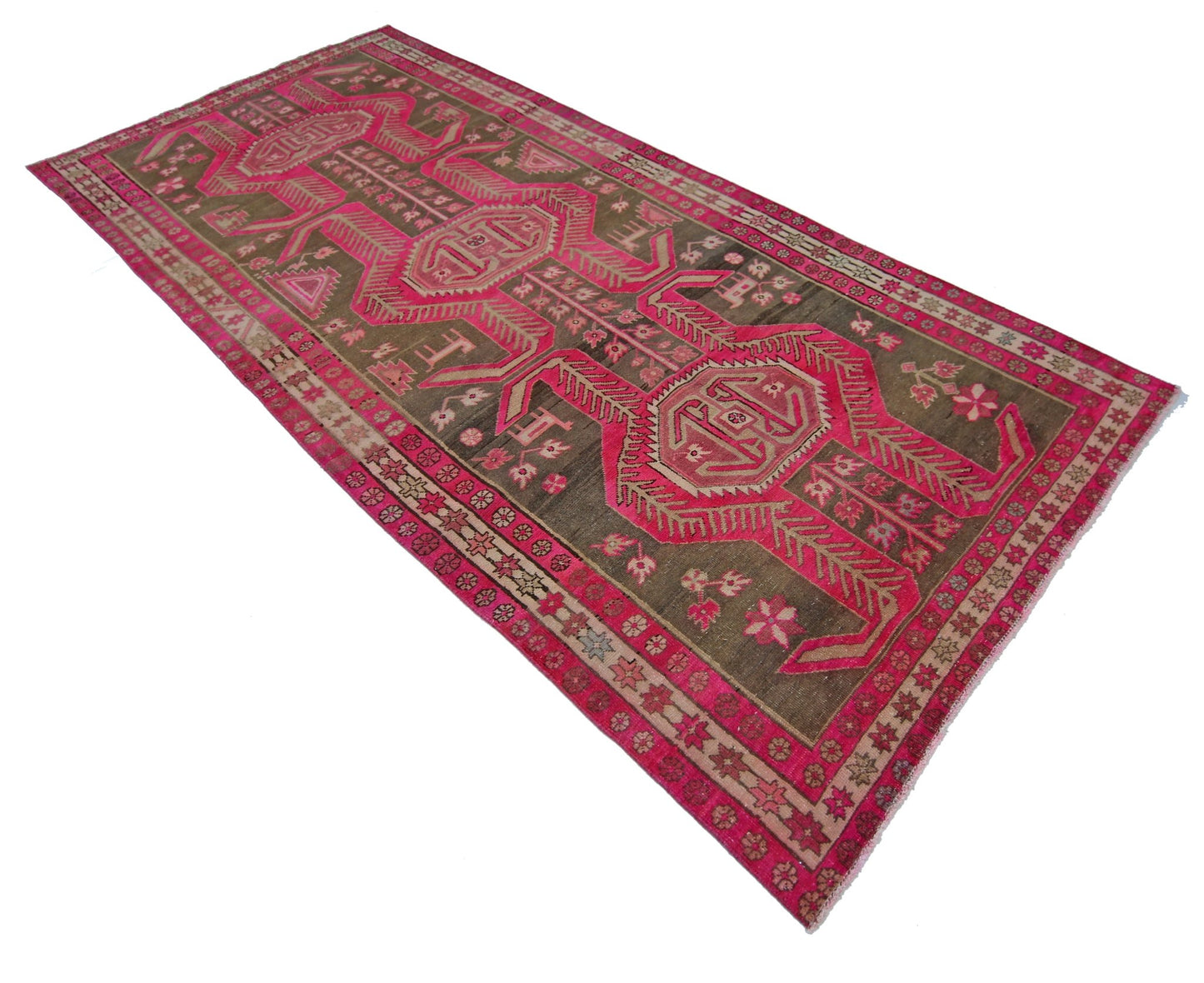 A vintage Persian Ardabil rug featuring geometric motifs in vibrant pink on a dark olive background.