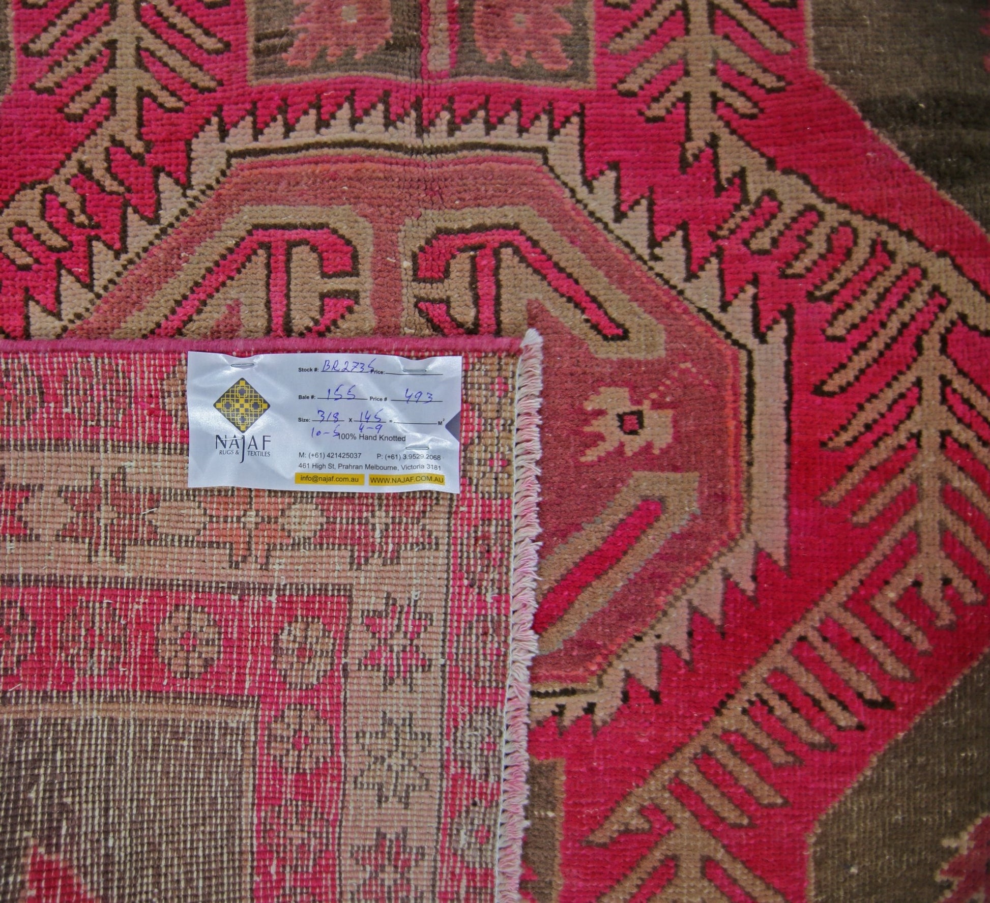 A vintage Persian Ardabil rug featuring a geometric pattern in vibrant pink and brown tones.