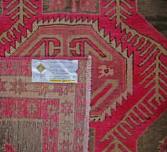 A vintage Persian Ardabil rug featuring a geometric pattern in vibrant pink and brown tones.