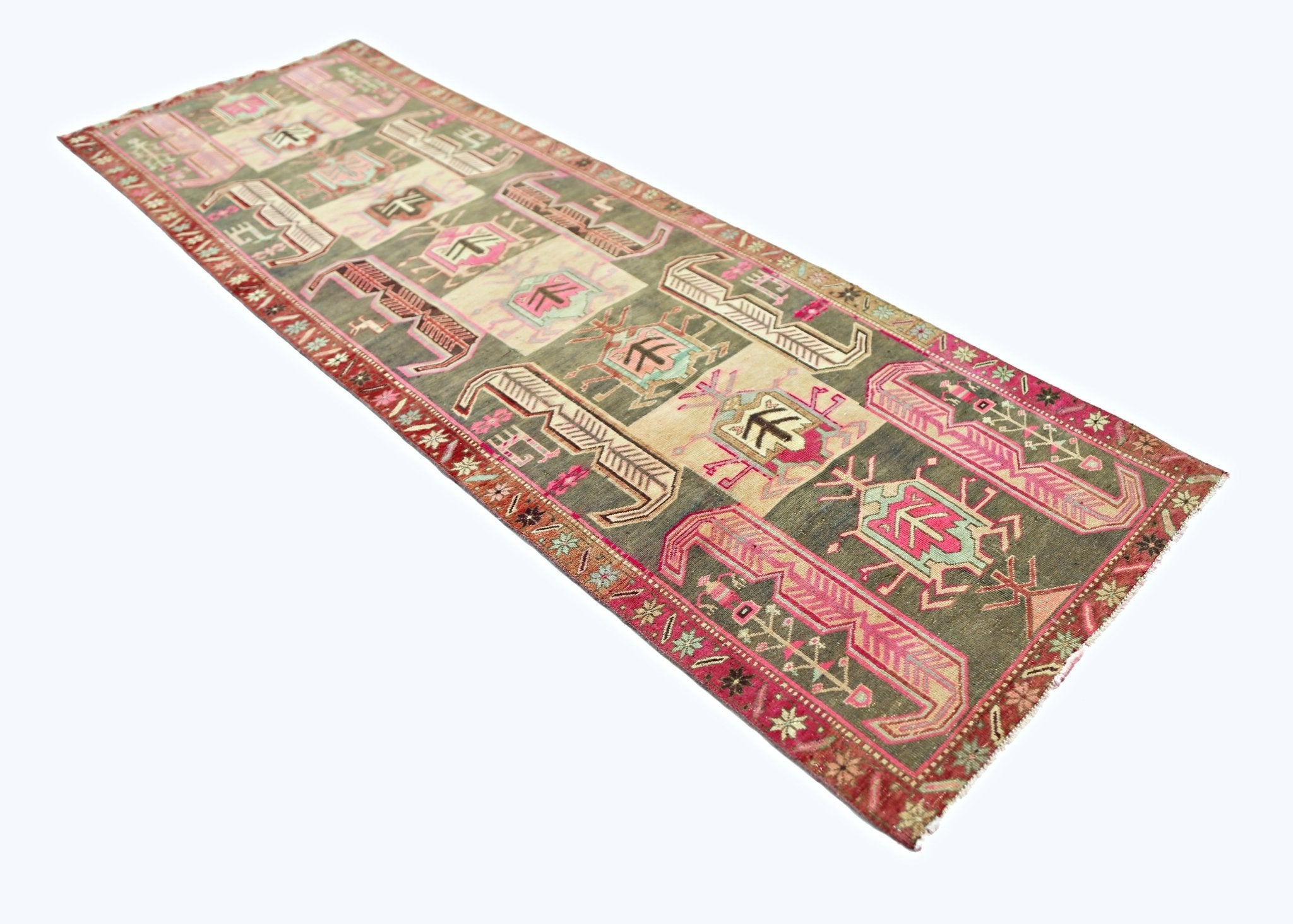 A vintage Persian Ardabil runner featuring geometric tribal motifs in muted green and pink tones.