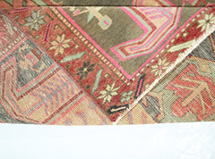 A folded vintage Persian Ardabil runner featuring intricate geometric patterns in red and green.