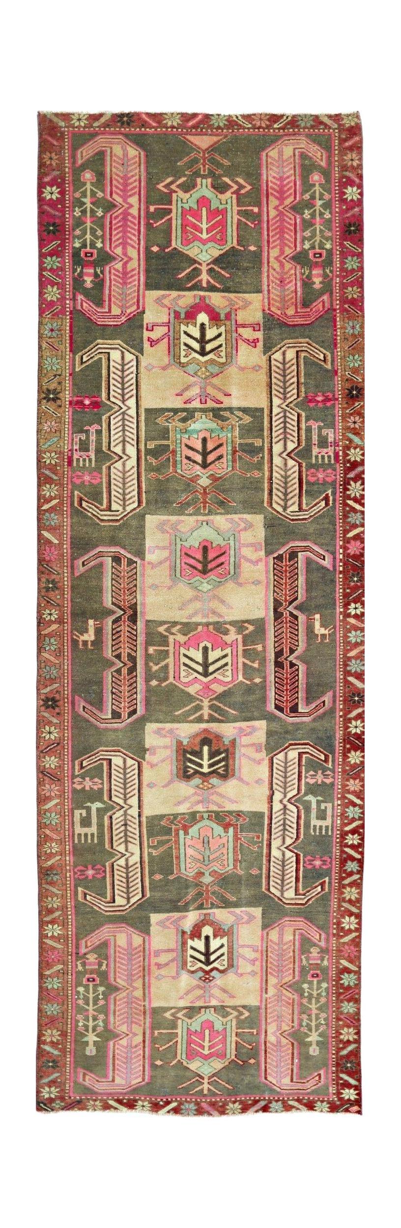 A vintage Persian Ardabil runner featuring geometric motifs in pink, green, and cream wool.