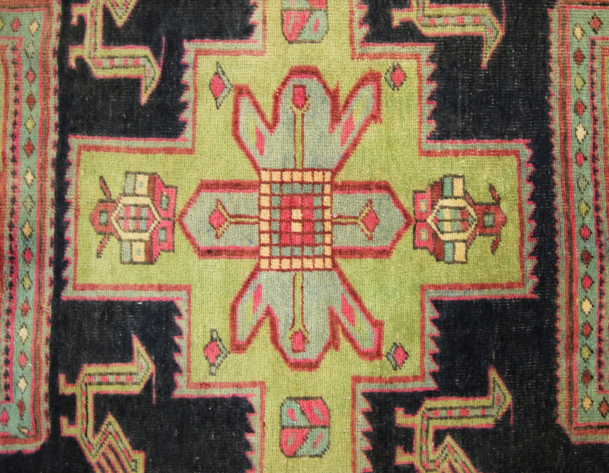 A vintage Persian Ardabil runner featuring a geometric green medallion on a dark blue background.