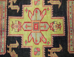 A vintage Persian Ardabil runner featuring a geometric green medallion on a dark blue background.