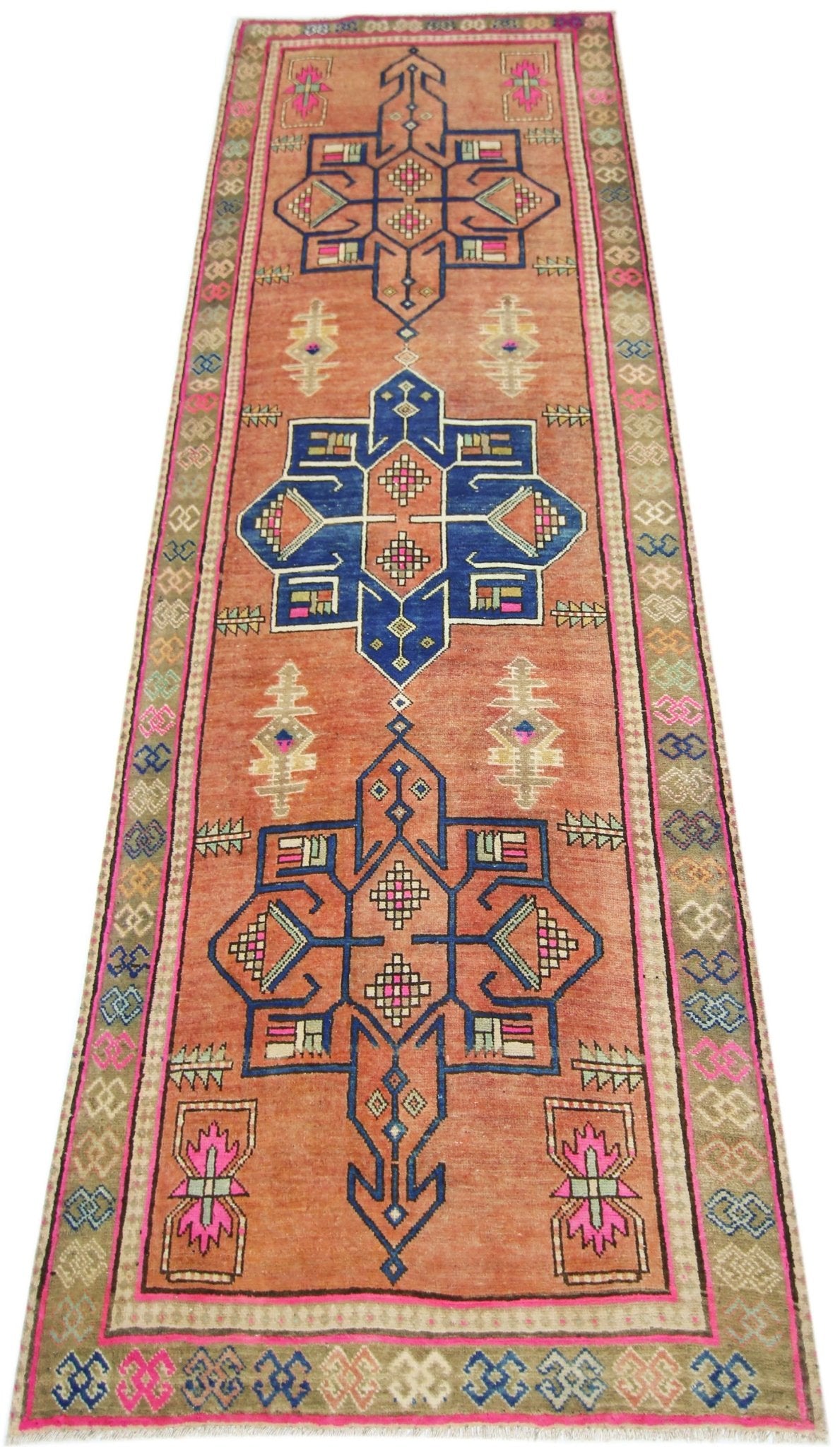 A vintage Persian runner featuring geometric medallions in blue and pink on an orange background.