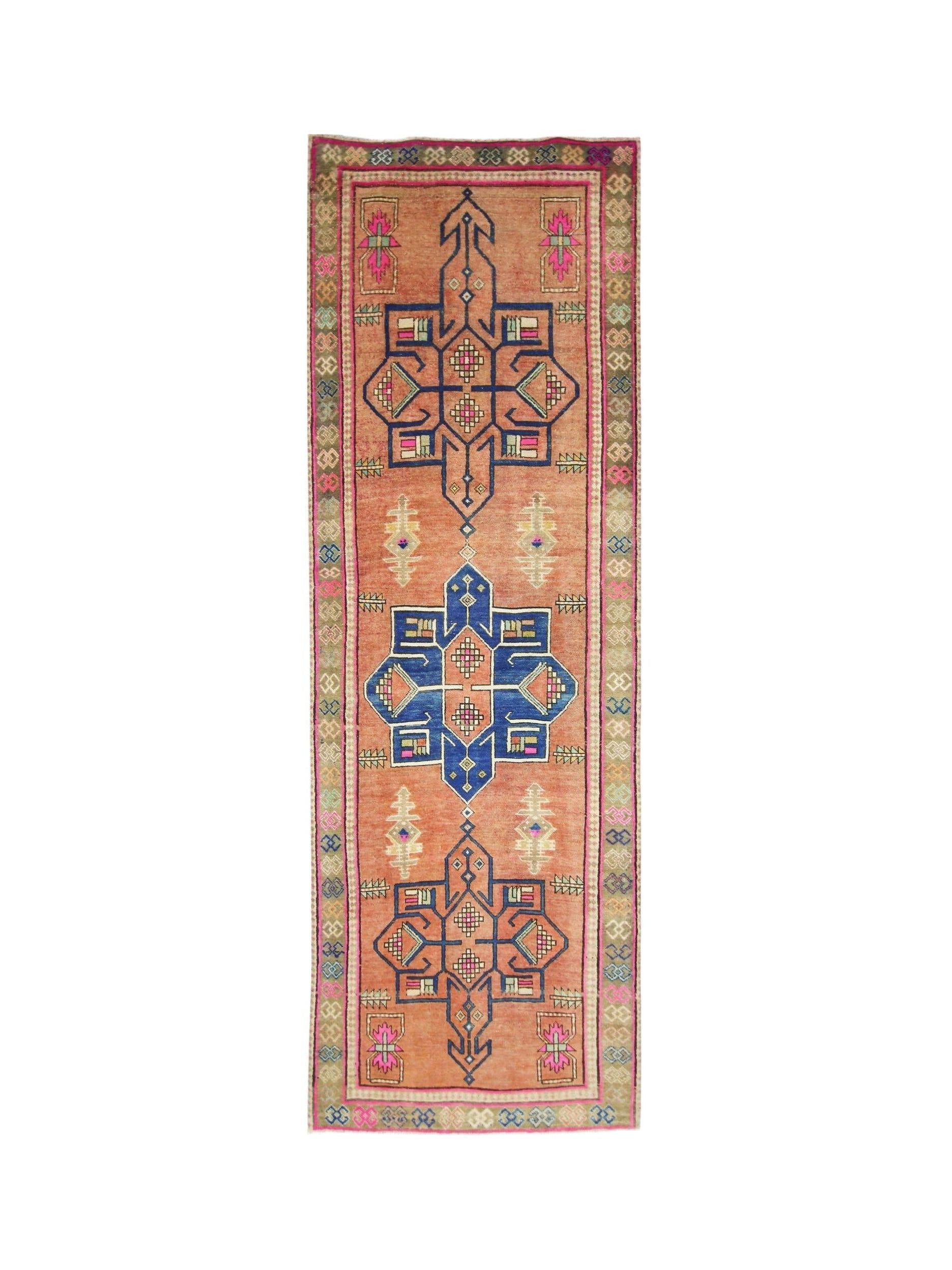 A handmade vintage Persian runner featuring geometric motifs in blue and pink on an orange field.