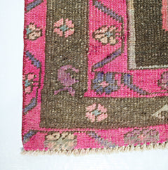 A vintage Persian Ardabil runner featuring a dark brown field with pink floral borders and fringe.