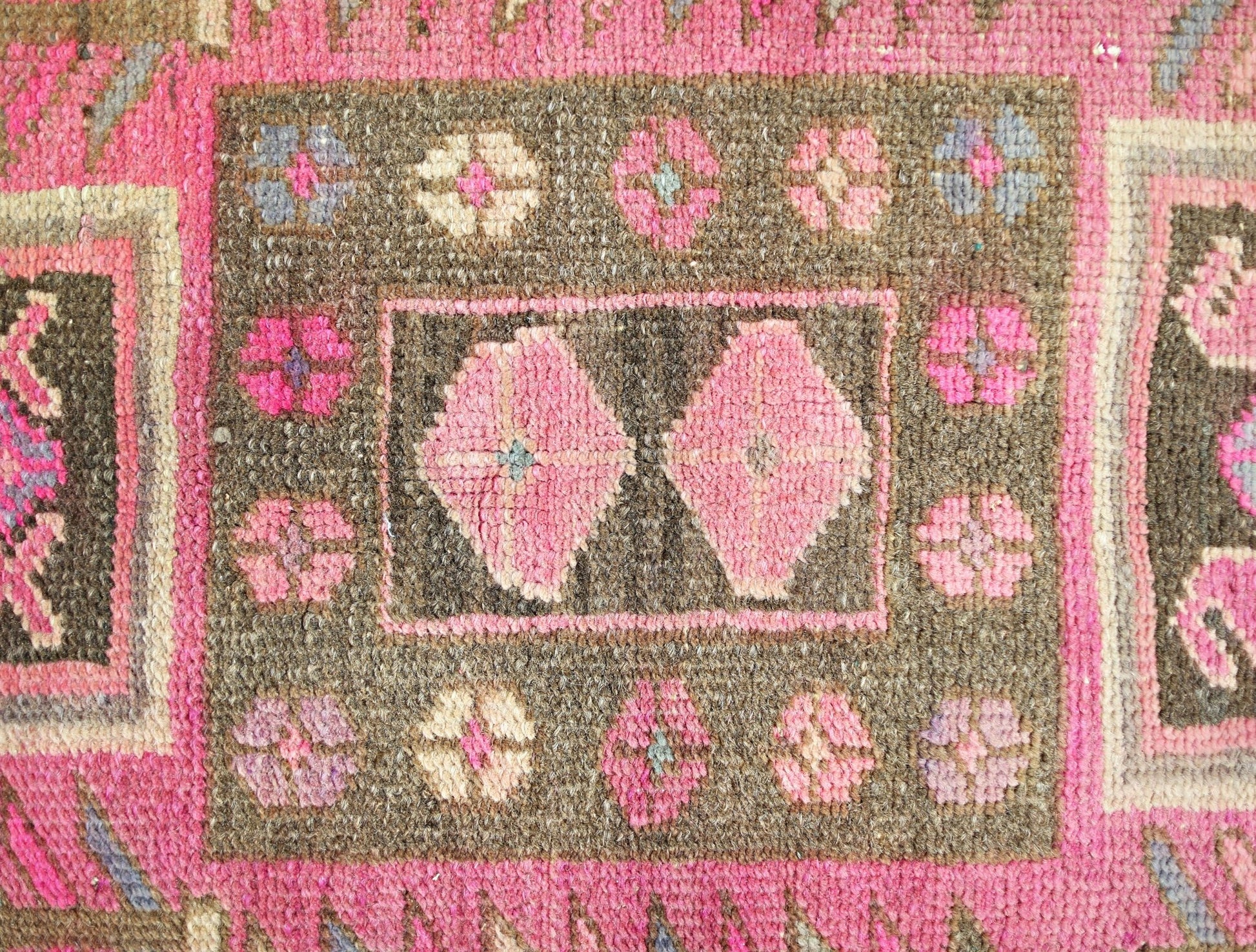 A vintage Persian Ardabil runner featuring a brown field with pink floral motifs and geometric shapes.
