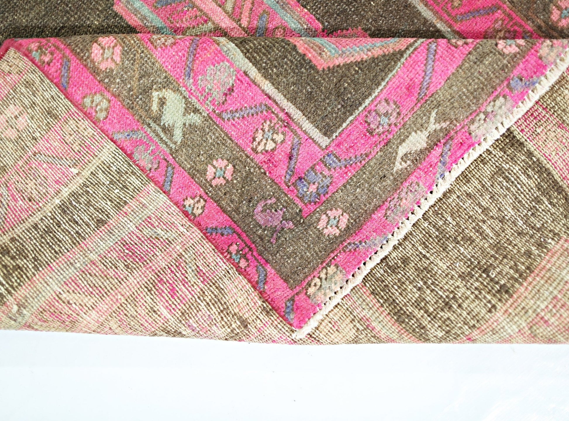 A vintage Persian Ardabil runner featuring a dark brown field with vibrant pink floral borders.