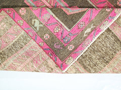 A vintage Persian Ardabil runner featuring a dark brown field with vibrant pink floral borders.
