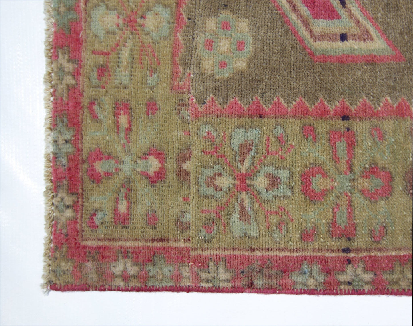 A vintage Persian Ardabil rug featuring a geometric floral pattern in muted green and pink tones.