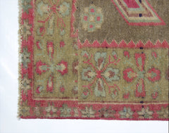 A vintage Persian Ardabil rug featuring a geometric floral pattern in muted green and pink tones.