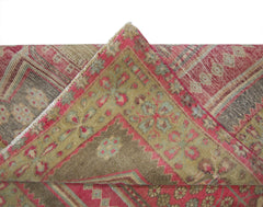 A vintage Persian Ardabil rug featuring a folded corner with intricate floral patterns in red and tan.