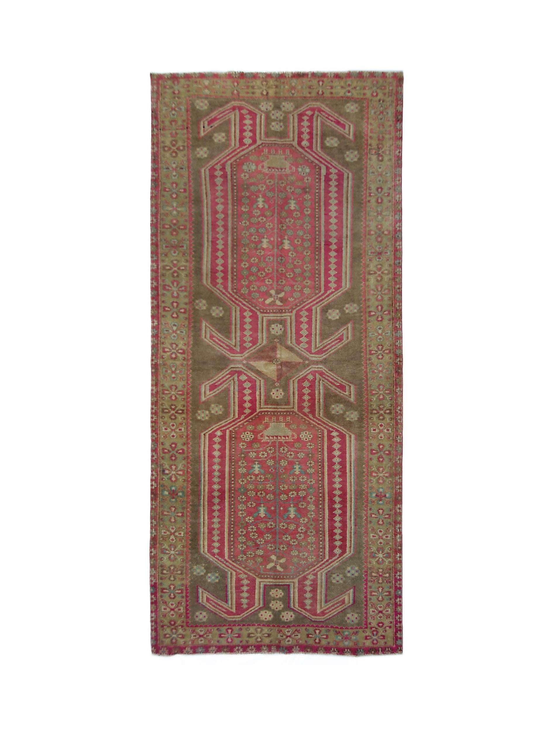 A vintage Persian Ardabil rug featuring a geometric pink and brown floral pattern.