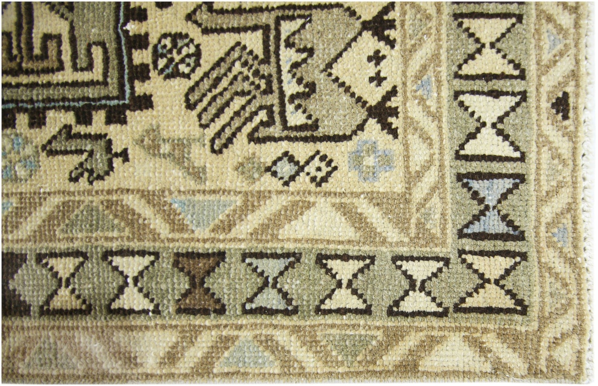 A close-up of a vintage Persian Ardabil runner featuring geometric patterns in muted earth tones.
