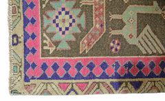 A vintage Persian Ardabil runner featuring a geometric pattern in pink, blue, and green on a brown field.