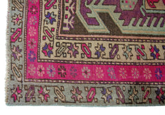 A vintage Persian Ardabil runner featuring a geometric pattern in vibrant pink, purple, and tan.