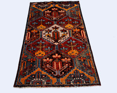 A vintage Persian Bakhtiari rug featuring a geometric floral pattern in vibrant red and blue tones.