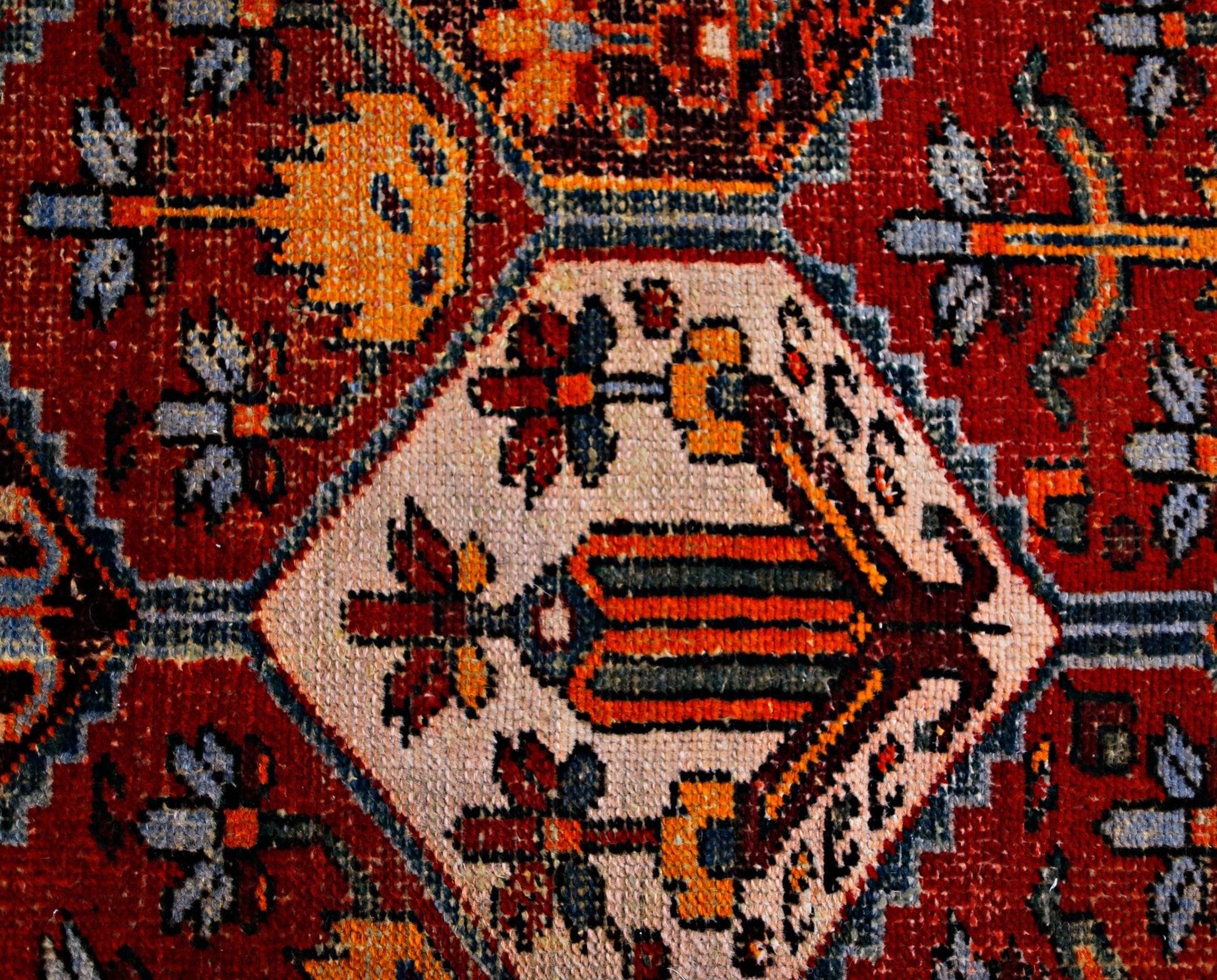 A close-up of a vintage Persian Bakhtiari rug featuring intricate floral motifs in red and cream.