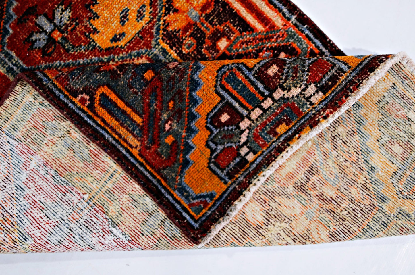 A folded vintage Persian Bakhtiari rug featuring intricate geometric patterns in vibrant colors.
