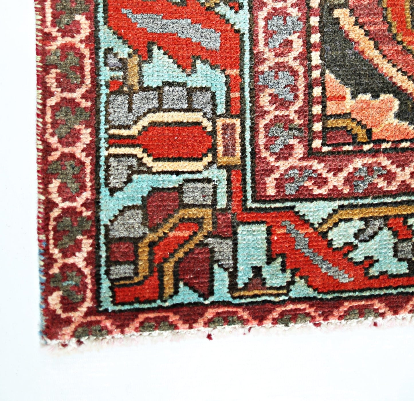 A corner view of a vintage Persian Bakhtiari rug featuring intricate geometric patterns in red and blue.