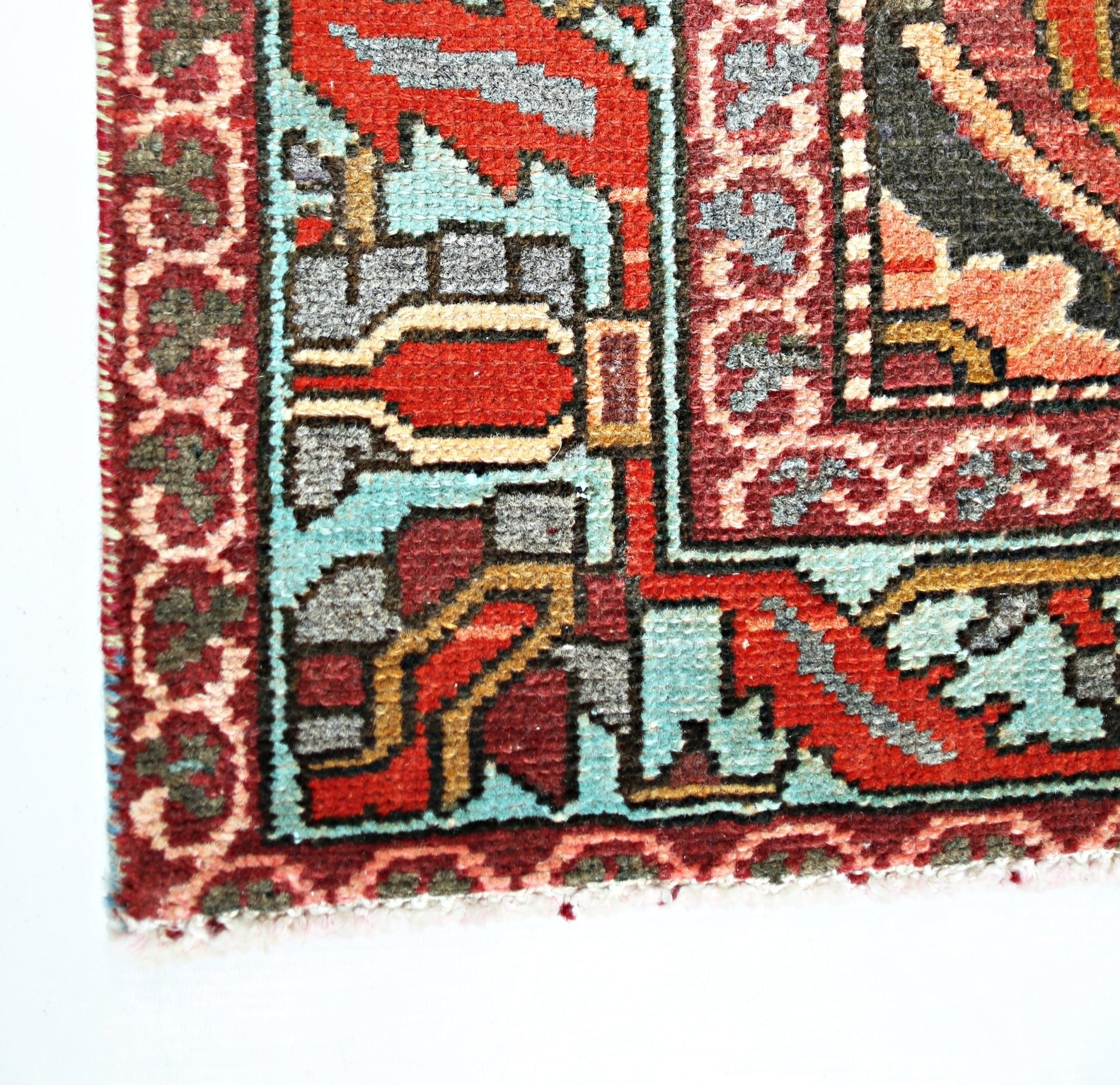 A corner view of a vintage Persian Bakhtiari rug featuring intricate geometric patterns in red and blue.
