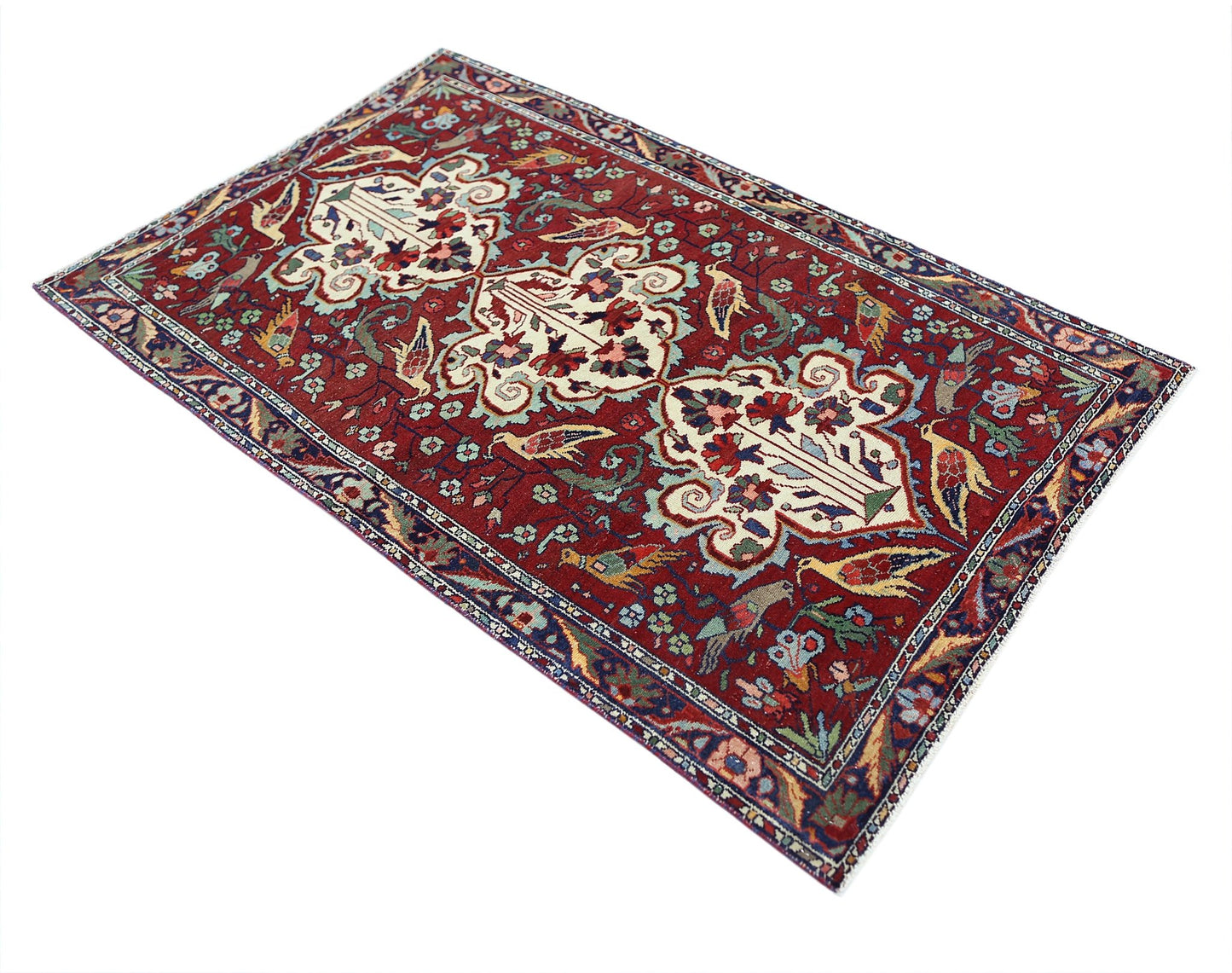 A vintage Persian Bakhtiari rug featuring a red field with intricate floral and bird motifs.