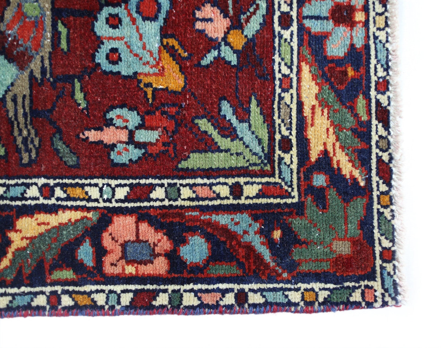 A corner view of a vintage Persian Bakhtiari rug featuring intricate floral and bird motifs.