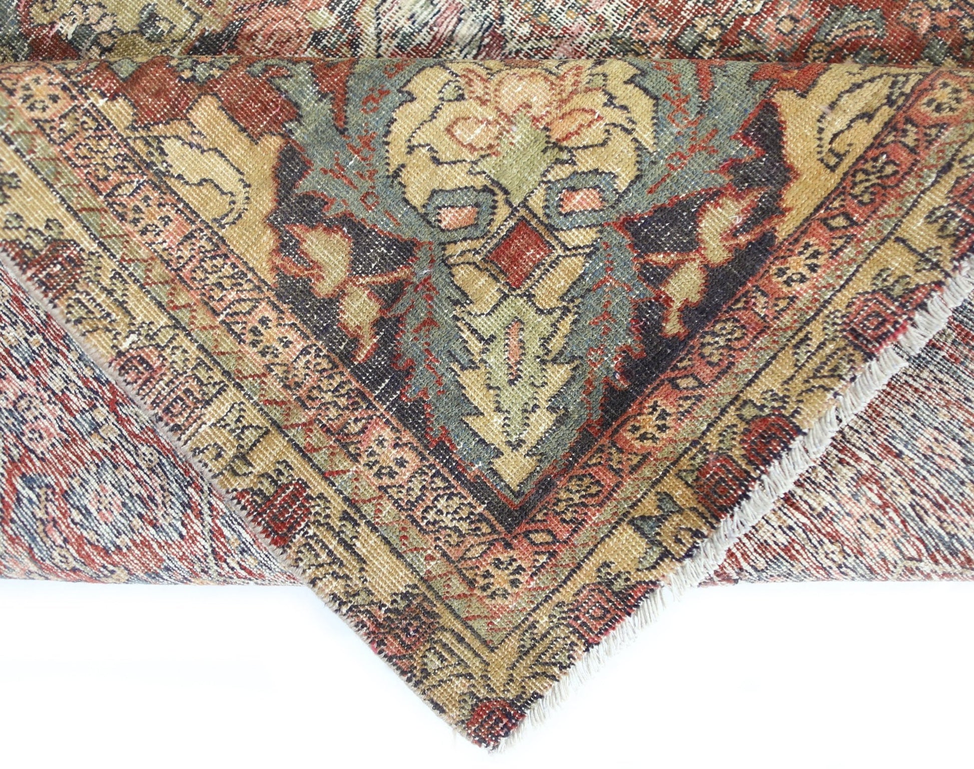 A folded vintage Persian Bakhtiari rug featuring intricate floral patterns in muted earth tones.