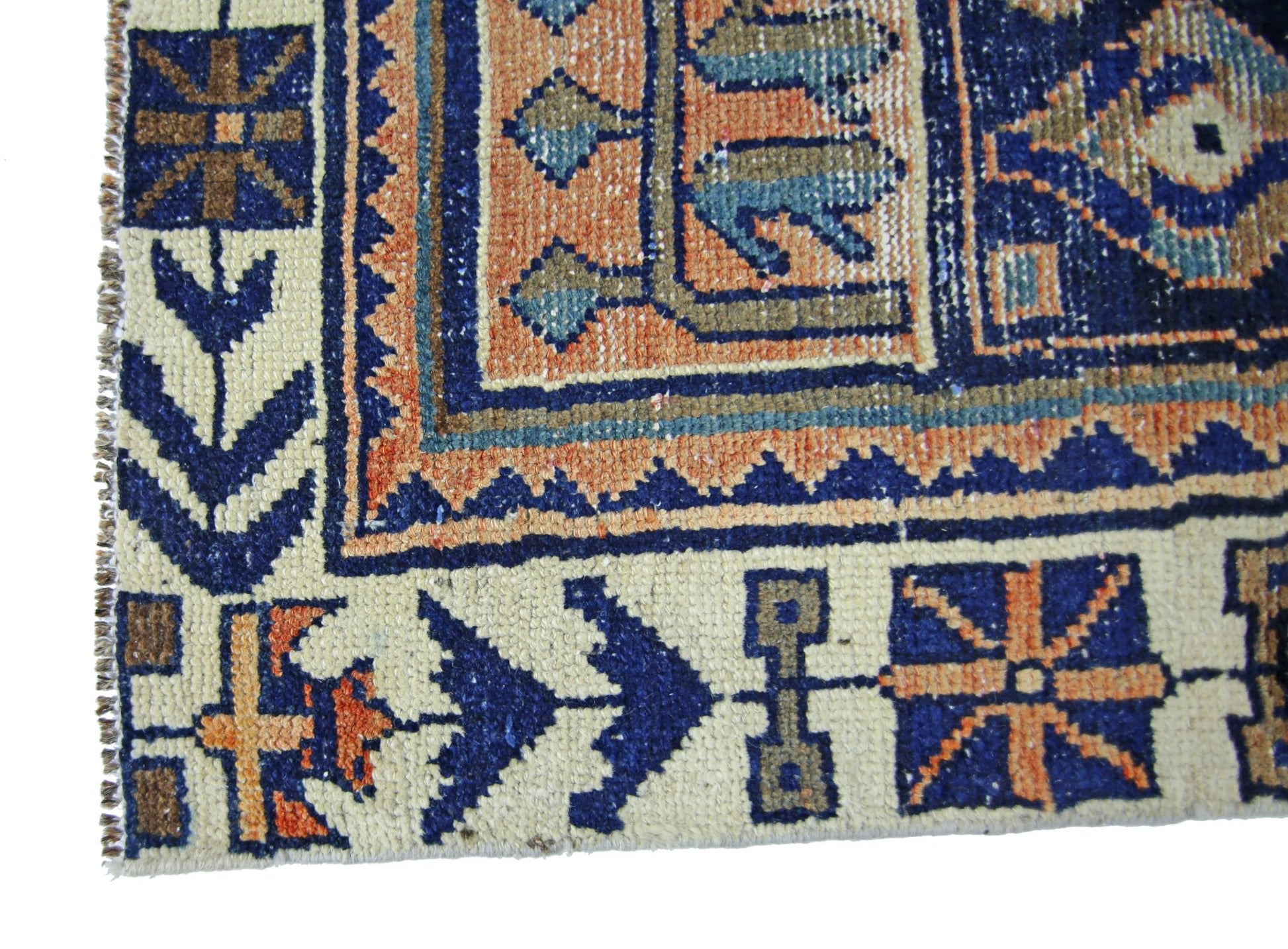 A corner detail of a vintage Persian Bakhtiari rug featuring geometric patterns in blue and orange.