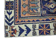 A corner detail of a vintage Persian Bakhtiari rug featuring geometric patterns in blue and orange.