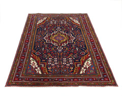 A vintage Persian Bakhtiari rug featuring a central medallion on a dark blue field with floral motifs.