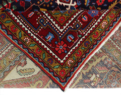 A folded vintage Persian Bakhtiari rug featuring intricate floral patterns in red, blue, and gold.
