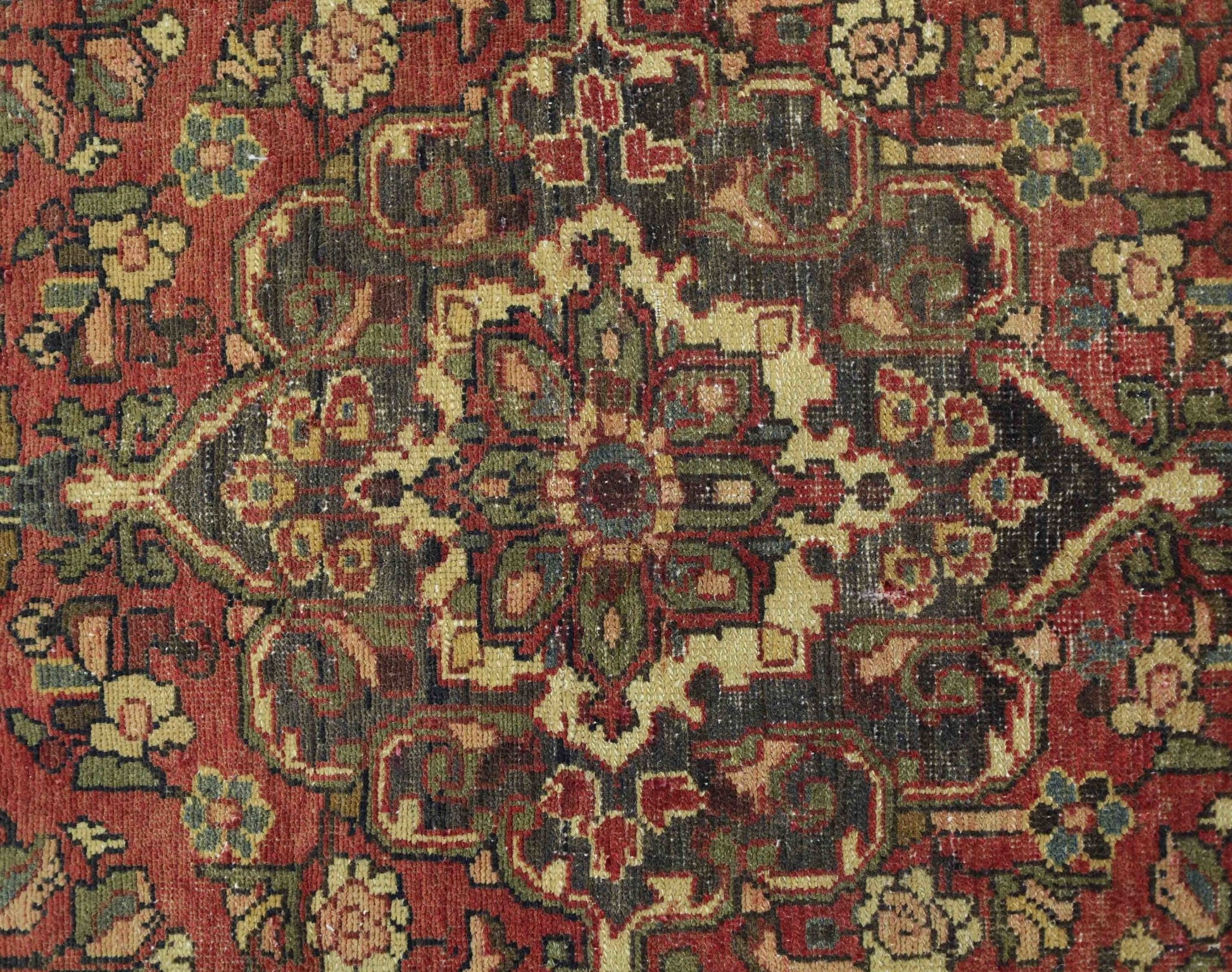 A vintage Persian Bakhtiari rug featuring a detailed floral medallion in red, green, and cream.