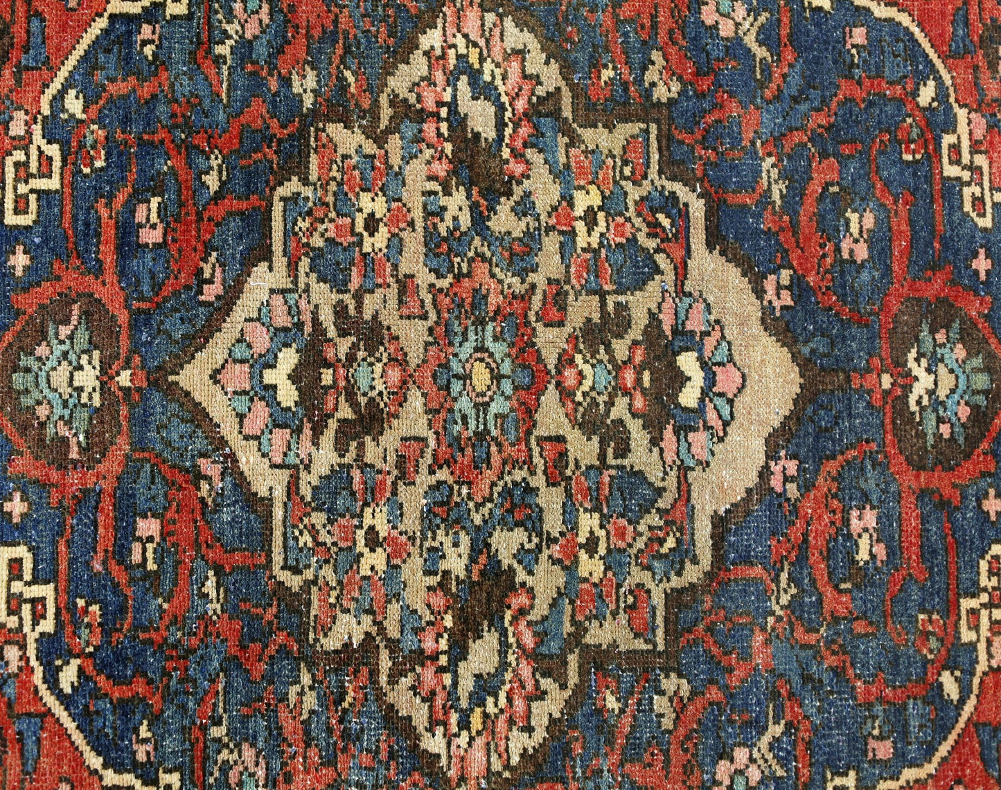 A vintage Persian Bakhtiari rug featuring a central floral medallion on a deep blue background.