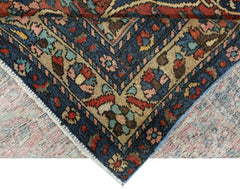 A corner of a vintage Persian Bakhtiari rug showing intricate floral patterns in blue and tan.