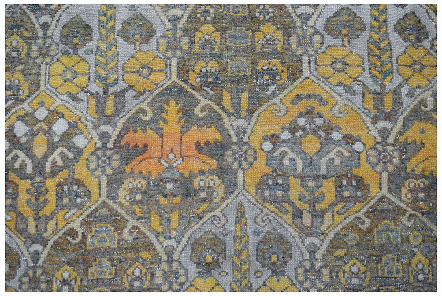A vintage Persian Bakhtiari rug featuring a repeating geometric pattern in yellow, grey, and orange.