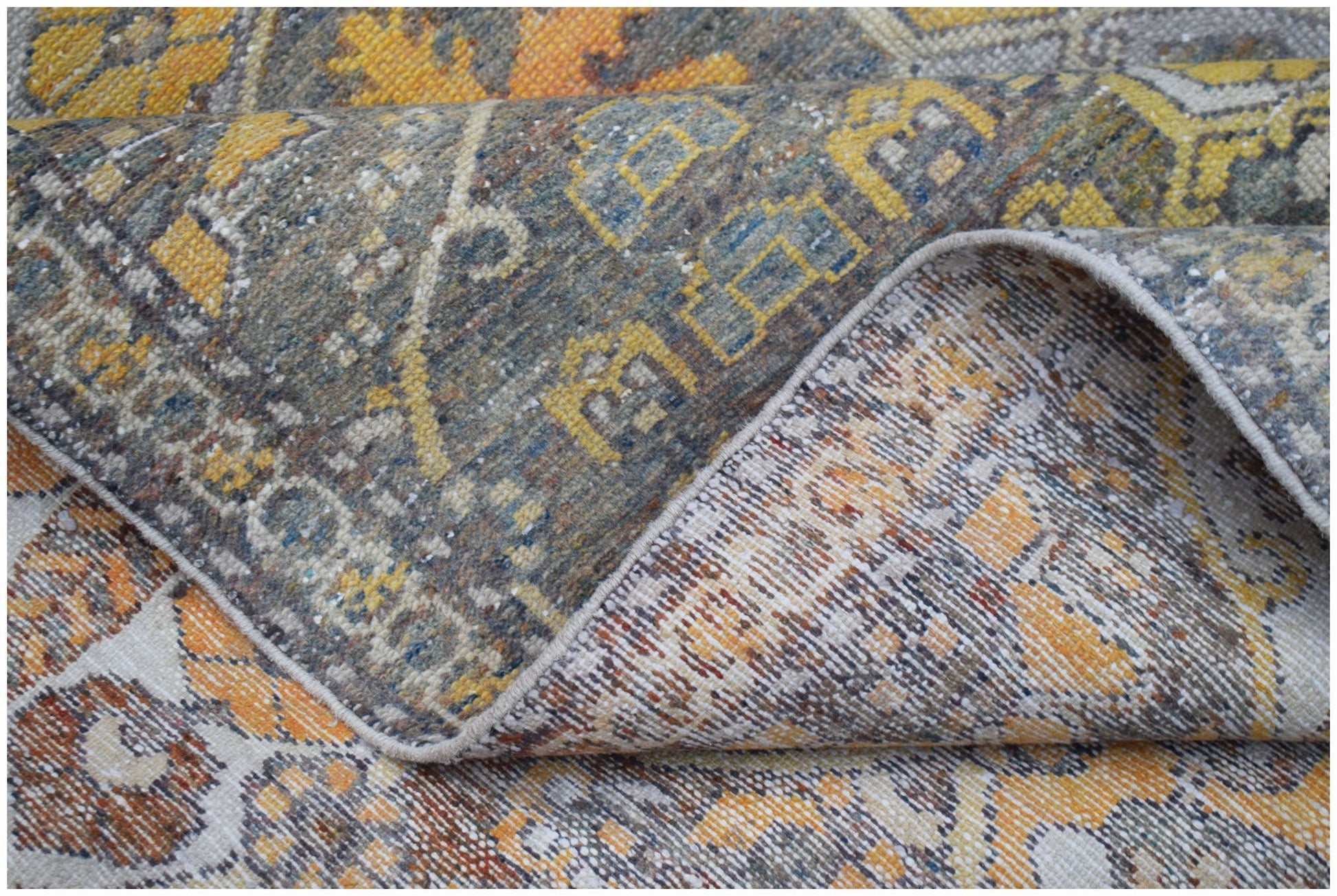 A vintage Persian Bakhtiari rug featuring a distressed floral pattern in yellow, grey, and orange.