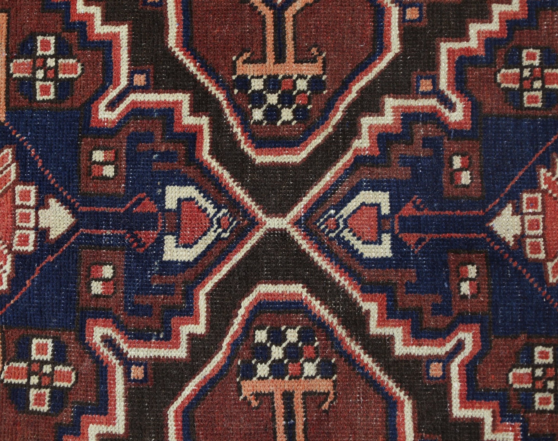 A close-up of a vintage Persian Bakhtiari rug featuring geometric floral motifs in red and blue.